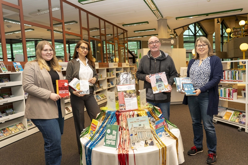 Lara Güdding und Nadine Müller von der Stabsstelle Zukunft Gladbeck, zweiter stellv. Bürgermeister Volker Musiol sowie Büchereileiterin Eva Beck eröffnen offiziell den neuen Büchertisch in der Stadtbücherei.