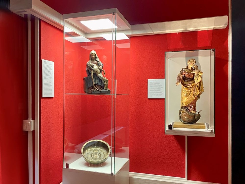 Eine der neuen Vitrinen im Museum Schloss Wittringen zeigt die trauernde Maria mit dem Jesuskind und eine Taufschüssel aus Messing.